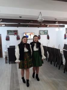 two girls are standing in front of a room with chairs at Pensiunea Popan in Şieu