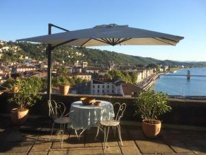 einen Tisch und Stühle unter einem Sonnenschirm auf dem Balkon in der Unterkunft La Bâtie in Vienne