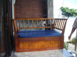 une chaise en bois avec un coussin bleu sur une terrasse couverte dans l'établissement Bubu Racok Homestay, à Amed