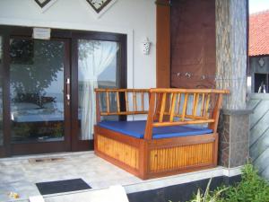 - une terrasse couverte avec un fauteuil à bascule sur le côté de la maison dans l'établissement Bubu Racok Homestay, à Amed