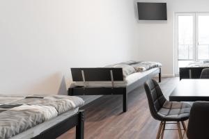 two beds in a room with a table and a chair at Monteurzimmer Berlin Pankow mit Dachterrasse - Nur 10 min. von der A10 - 3 Zimmer/ 7 Betten in Berlin +17 photos