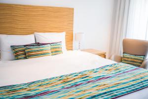 a white bed with a colorful striped blanket and pillows at Guest House Le Charlot in Vevey