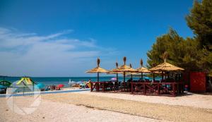 a group of tables with umbrellas on the beach at Apartments Nautilus in Pula