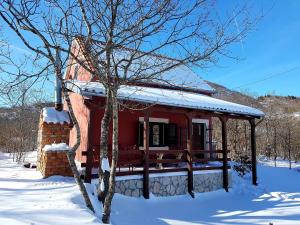 a red house with a porch in the snow at Holiday Home Nikolić in Njeguši