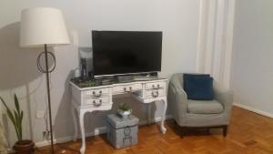 ein Wohnzimmer mit einem TV und einem Stuhl in der Unterkunft Apartamento 2Quartos PraiaMetro Copacabana in Rio de Janeiro