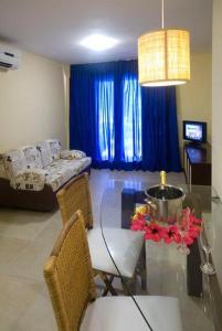 een woonkamer met een glazen tafel en blauwe gordijnen bij RESORT SOLAR PIPÁ CASA 24 in Pipa