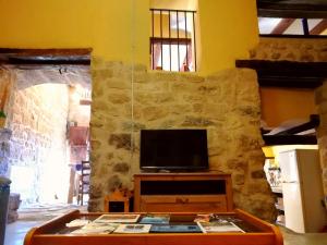 ein Wohnzimmer mit einem TV an einer Steinmauer in der Unterkunft Casa Marina in Valderrobres