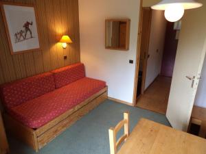 a red couch in a room with a table at Valmorel Studio Skis aux pieds in Valmorel +24 photos