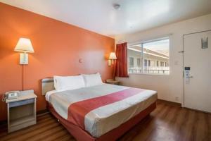 a bedroom with a large bed with an orange wall at Motel 6 Wendover in Wendover