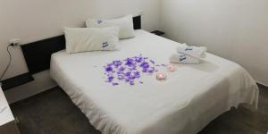 Una cama blanca con flores moradas encima. en B&B IONA, en Rocca di Neto