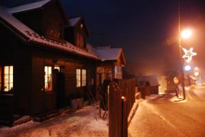 a house on a snowy street at night at Domek w górach do wynajęcia i pokoje in Piwniczna-Zdrój