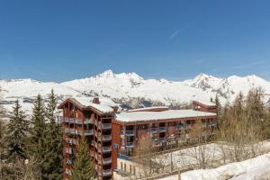 a hotel with snow covered mountains in the background at Appartement Le Thuria in Arc 1800