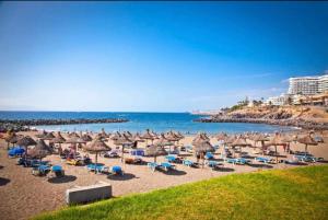 a beach with umbrellas and chairs and the ocean at Pueblo Canario Loft In Las Americas in Playa Fañabe