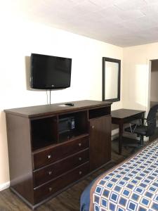 a hotel room with a dresser with a television on it at Express Inn in Lafayette