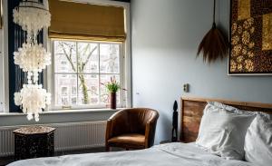 a bedroom with a bed and a chair and a window at Rosalia's Menagerie Cocktail bar & InnUpstairs in Amsterdam