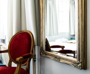einen Spiegel mit Stuhl und ein Bett in einem Zimmer in der Unterkunft Rosalia's Menagerie Cocktail bar & InnUpstairs in Amsterdam