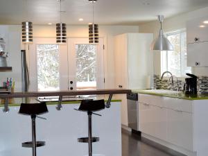 a kitchen with white cabinets and a counter with stools at La Maison jaune de Chute-Saint-Philippe in Lac-Saint-Paul