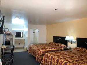 a hotel room with two beds and a desk at Luxury Inn in Norwalk