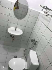 een witte badkamer met een toilet en een wastafel bij Meaco Royal Hotel - Malabon in Manilla
