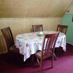 mesa de comedor con mantel y sillas blancas en Casa Lange, en Valdivia