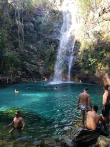 a group of people in the water in front of a waterfall at Hotel Recanto Verde in Teresina de Goias