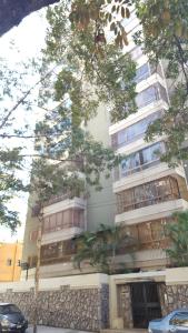 a tall white building with trees in front of it at apartosuite Sabana Grande in Caracas