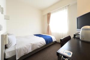 a hotel room with a bed and a desk and a window at Uwajima Oriental Hotel in Uwajima