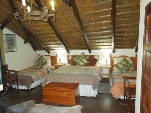 una camera con due letti in una stanza con soffitti in legno di Trees Too Guest Lodge a Komatipoort