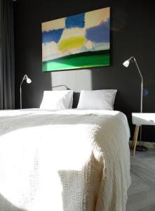 um quarto com uma cama branca com 2 candeeiros e um quadro em Hus em Leeuwarden
