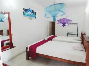 Jayaru Guest House في بولوناروا: سريرين في غرفة مع مظلات على الحائط