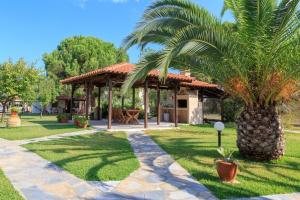 a palm tree in front of a house with a pavilion at Maria - Pavlos Studios and Apartments in Vourvourou