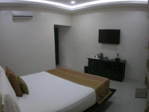 a bedroom with a bed and a tv on the wall at AJ's Place Beach Resort in Oslob