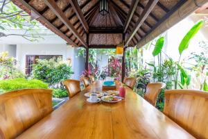 een eetkamer met een houten tafel en stoelen bij Gatra Ubud Inn in Ubud