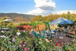 a garden with a table and an umbrella and flowers at Hahar Aatzil in H̱azon