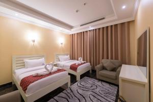 une chambre d'hôtel avec deux lits et une chaise dans l'établissement Rose Suite Operated by Suite Hotel Management, à Djeddah