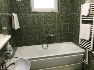 ein grün gefliestes Bad mit einer Badewanne und einem Waschbecken in der Unterkunft Pension Eclipse in Oradea