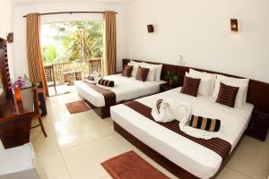 a hotel room with two beds and a balcony at Dickwella Beach in Dickwella