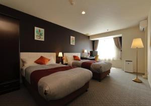 a hotel room with two beds and a window at Garden hotel Shiunkaku Higashimatsuyama in Higashimatsuyama