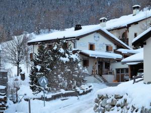 ein schneebedecktes Gebäude mit einem Weihnachtsbaum davor in der Unterkunft Chesa Sper l'Ovel Brail in Zernez