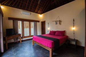 a bedroom with a pink bed and a television at Rindu Villa in Nusa Lembongan