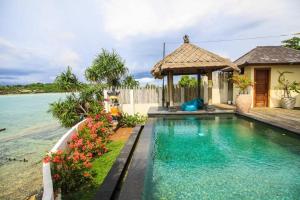 a villa with a swimming pool next to the ocean at Rindu Villa in Nusa Lembongan