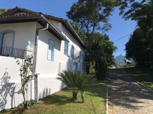 a white house with a palm tree next to a street at Pousada Almaviva in Ilha de Boipeba