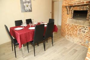 une salle à manger avec une table rouge, des chaises et un mur en briques dans l'établissement Maison de l'horloge, à Courcelles-sous-Moyencourt