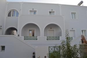 a woman sits on the ledge of a white building at Altea Apartments in Fira