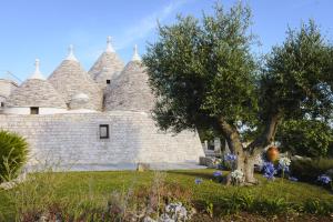 a stone building with a tree in the yard at Trulli Angela in Locorotondo