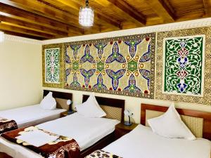 a room with two beds and a mosaic wall at Sukhrob Barzu Hotel in Bukhara