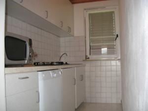 a white kitchen with a sink and a microwave at Apartments Silmare in Rabac