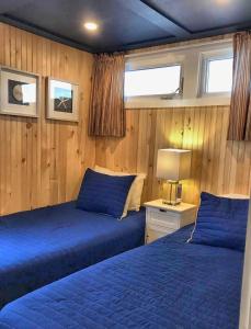two beds in a bedroom with wood paneling at Chalet 44 in Grand Barachois