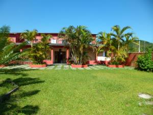 a house with palm trees in front of a yard at Residencial Candairó in Cananéia