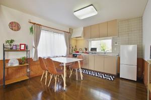 Una cocina con mesa y sillas y un refrigerador. en Villent Fujimi Hiekawa, en Izu